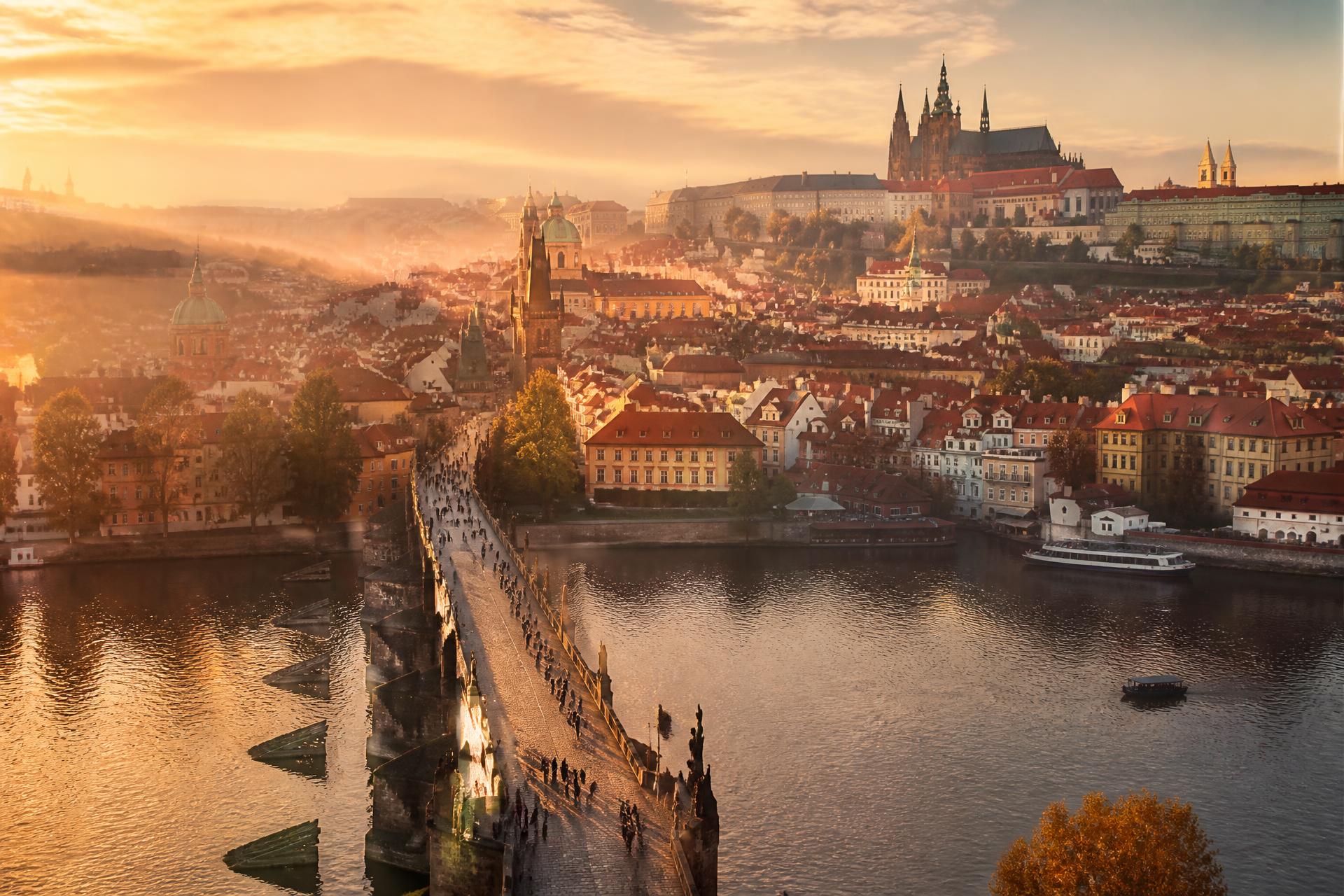 Golden-hour aerial view of Prague with Charles Bridge and Prague Castle